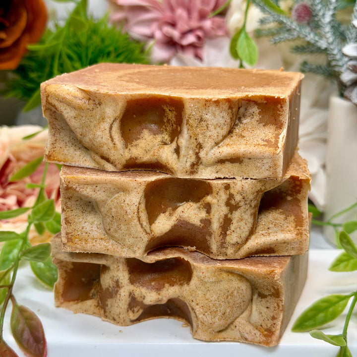 Stack of brown soap bars with a floral and greenery background