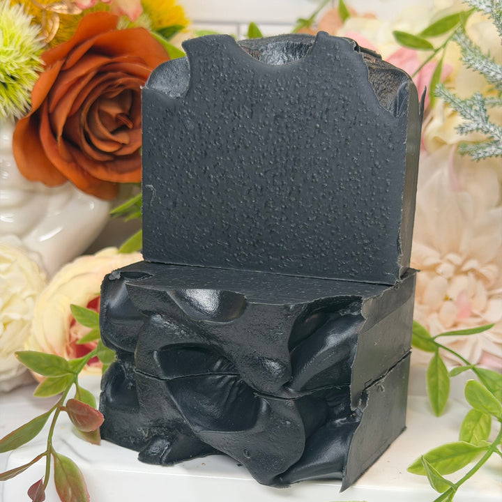 Black soap bar with decorative flowers and greenery in the background