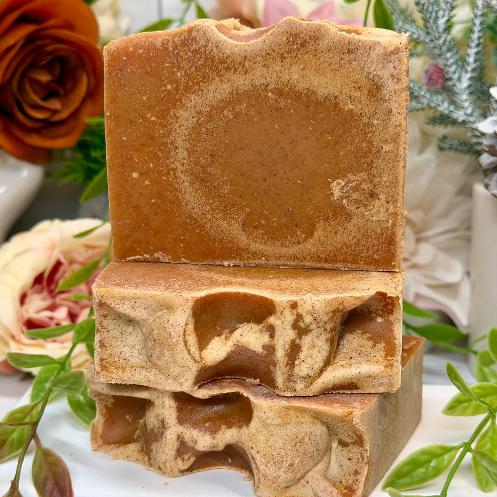Stack of brown soap bars with floral and greenery in the background