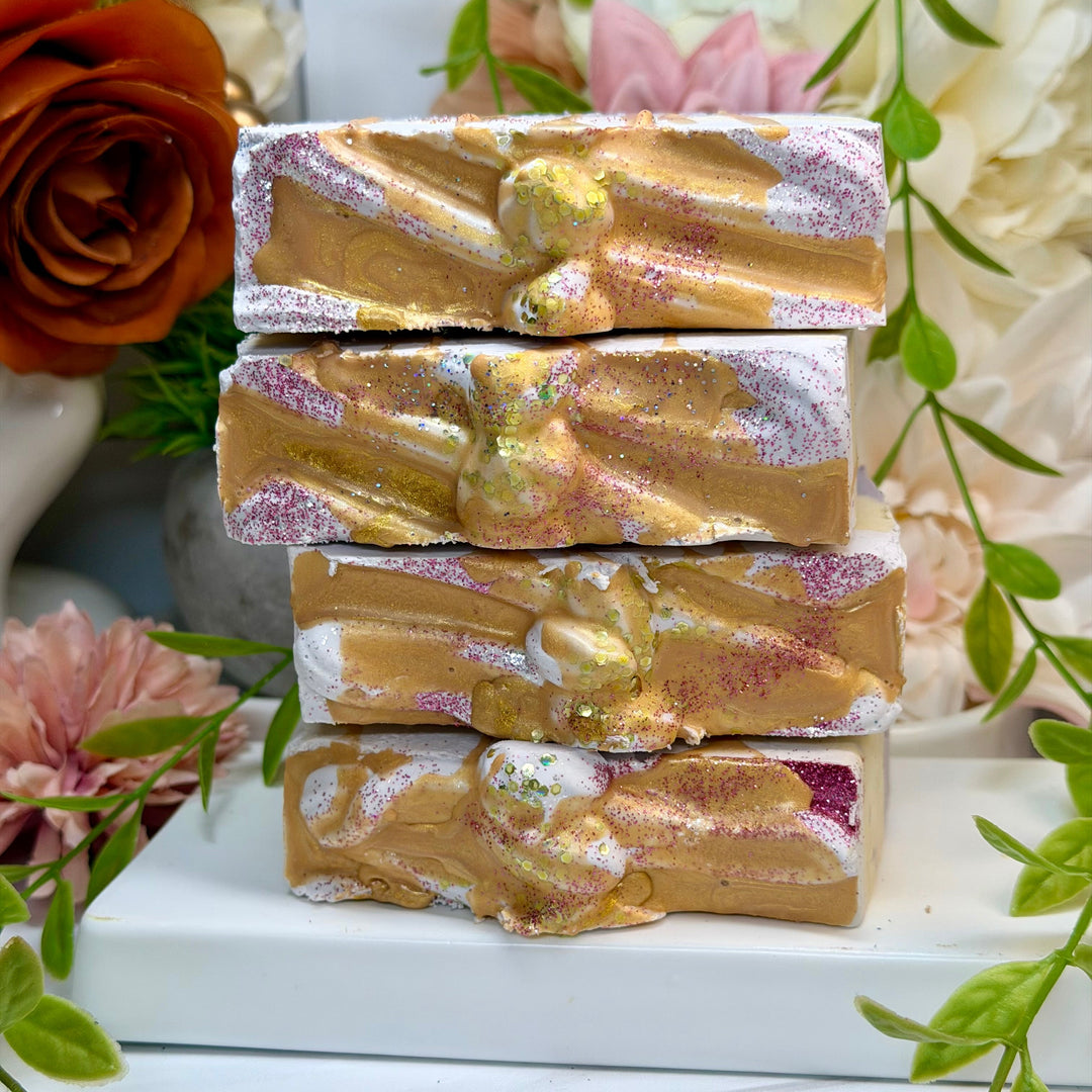 Stack of gold and silver swirled soap bars with flowers in the background