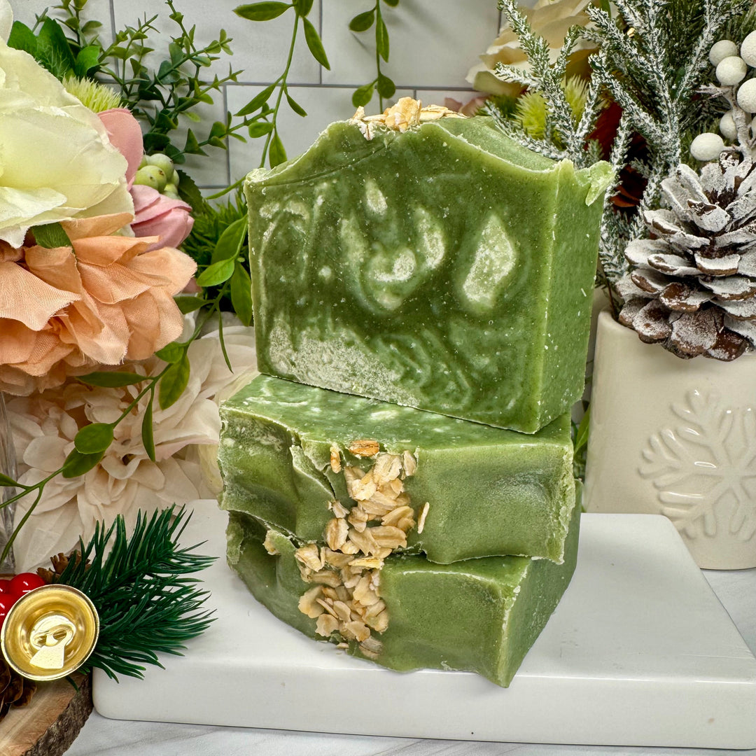 Green soap bar with natural texture on a white surface with decorative elements.