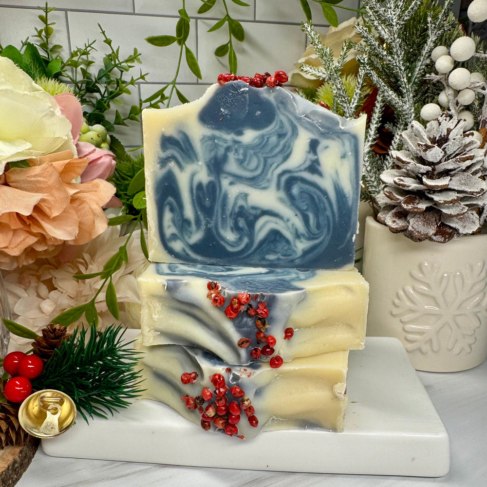Decorative soap bar with blue and white swirls on a marble stand, surrounded by festive decorations.