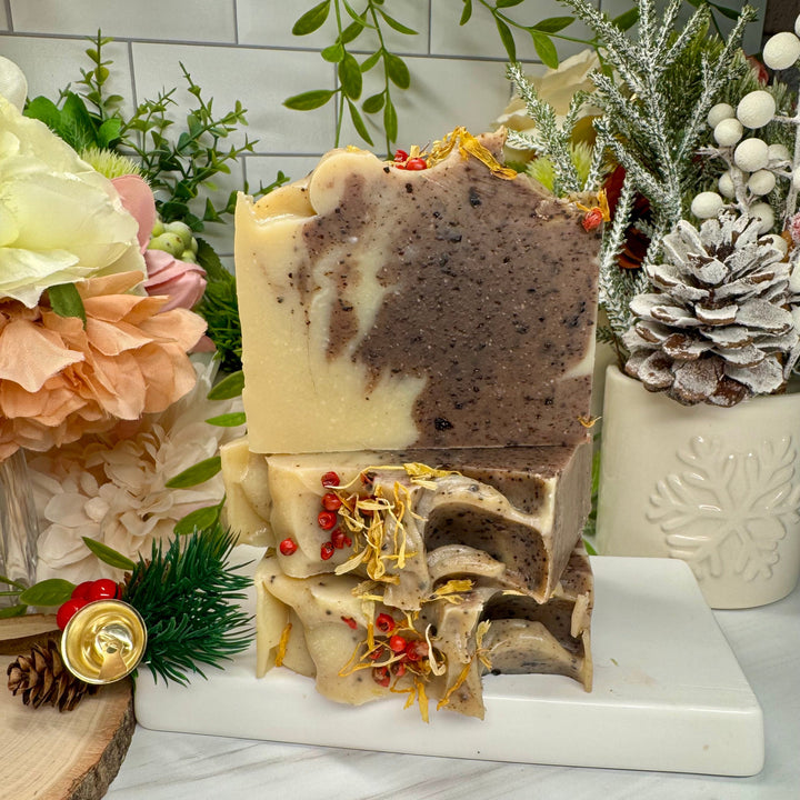 Decorative soap bar with natural elements on a marble stand, surrounded by flowers and plants.