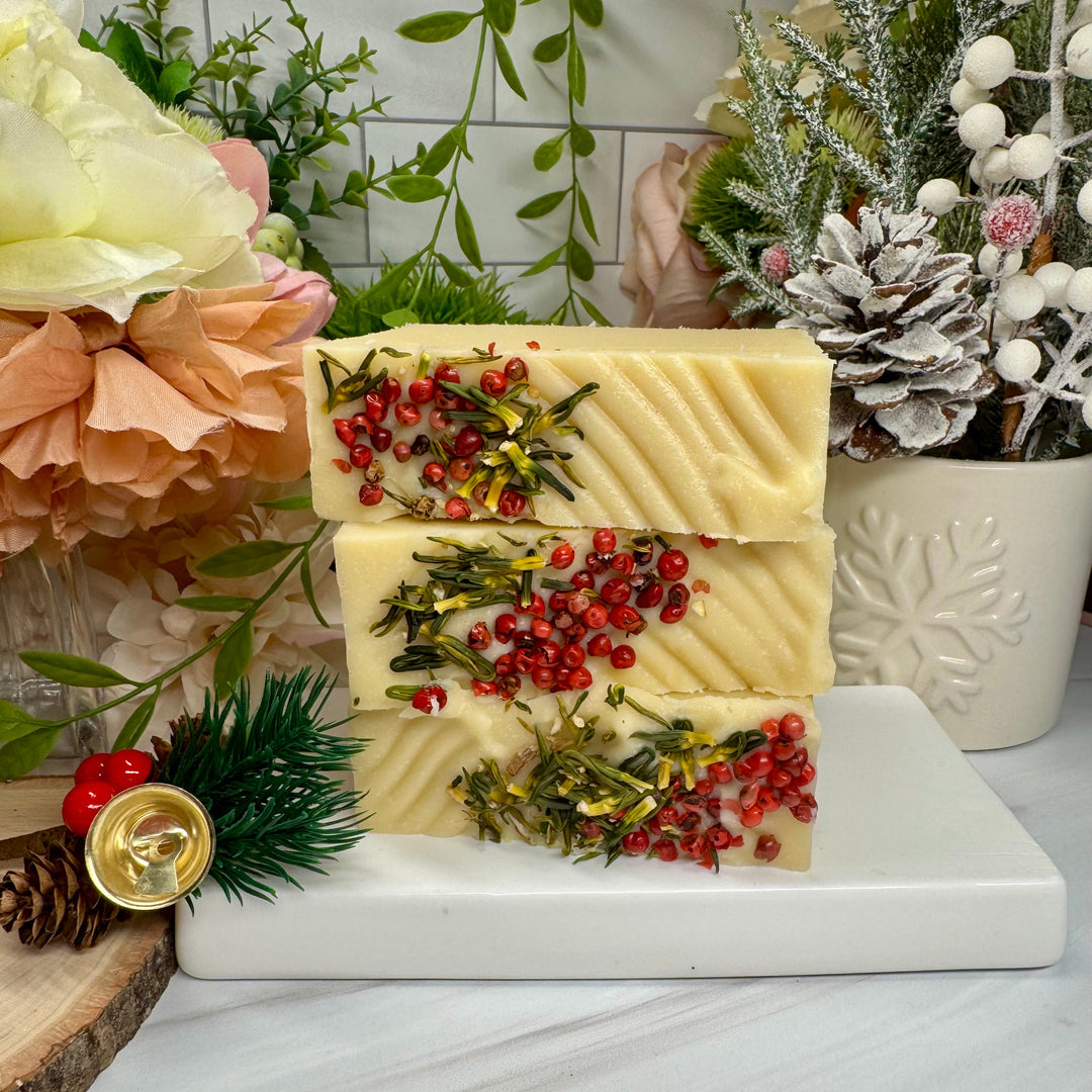 Decorative soap with red berries and greenery on a marble surface with floral and plant decorations.