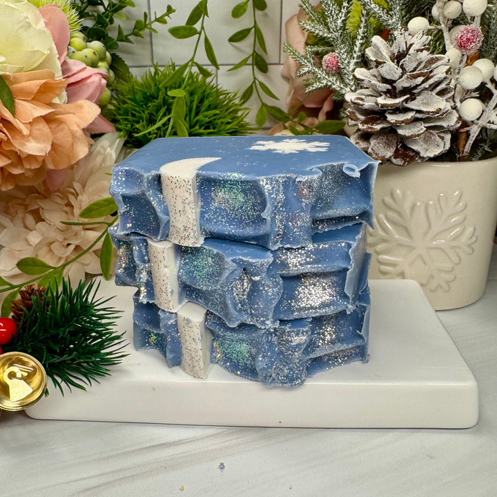 Stack of blue soap bars with white specks on a white surface with decorative elements.