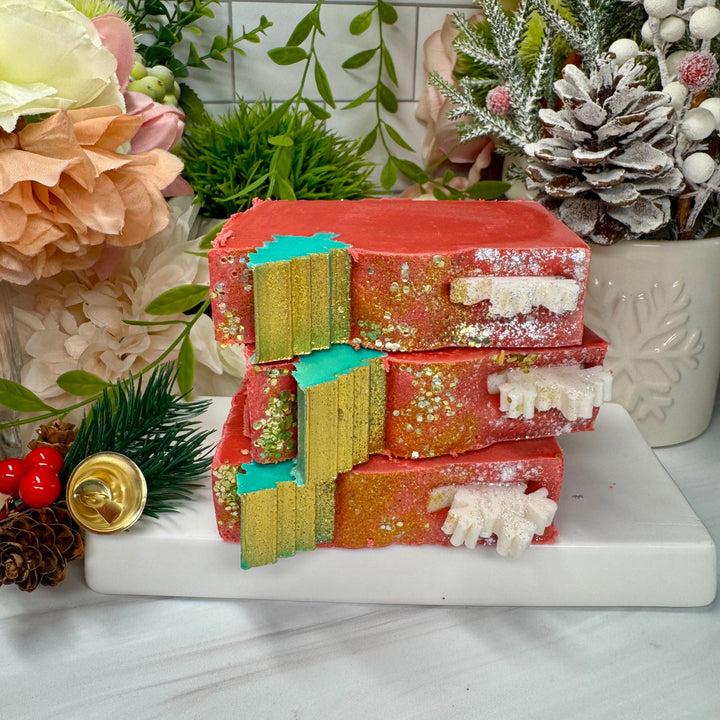 Stack of colorful soap bars on a marble surface with decorative plants and flowers in the background.