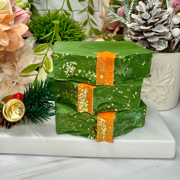 Stack of green soap bars with orange accents on a marble surface with decorative elements.