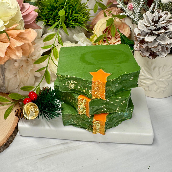 Decorative green soap with gold accents on a white surface with floral and greenery Christmas holiday background