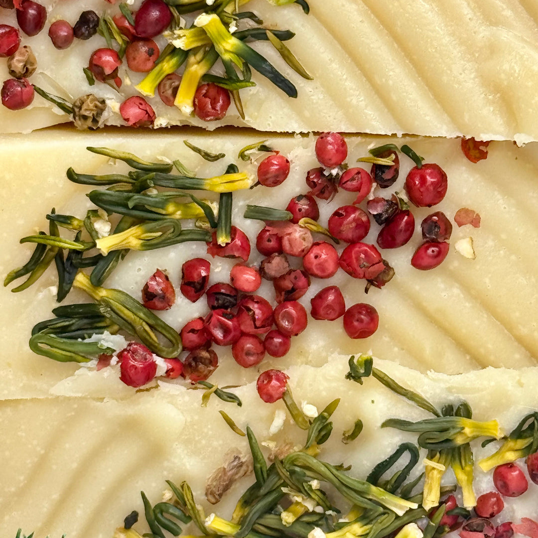 Close-up of a dish with green herbs and red berries on a textured surface