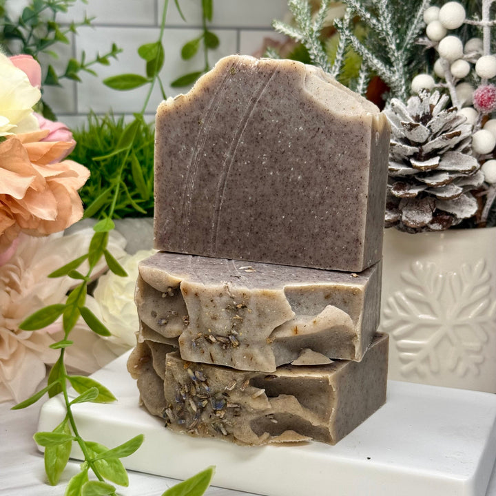 Stack of handmade soap bars on a white marble slab with decorative elements in the background.