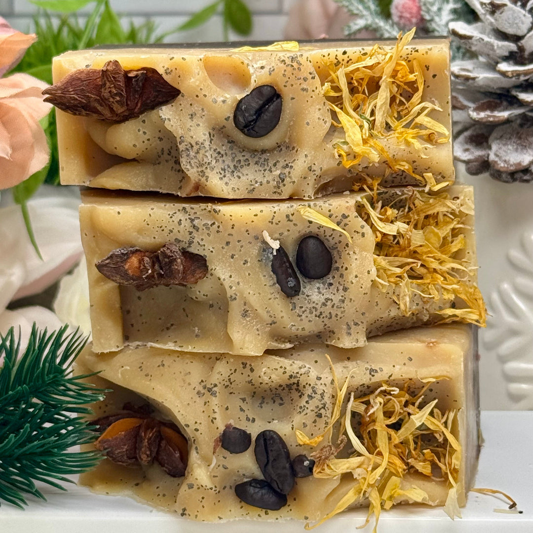 Three layered soap with natural ingredients on a white surface with greenery in the background